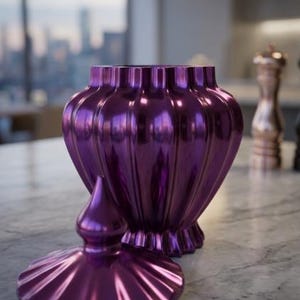 May include: A decorative, glossy purple jar with a matching lid. The jar has a fluted design and a bulbous shape, suitable for storage or display. The lid is off to the side, revealing the interior.
