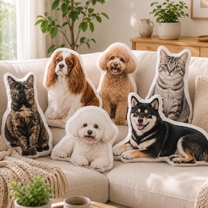 May include: A collection of six decorative throw pillows shaped like various animals, including a tortoiseshell cat, a Cavalier King Charles Spaniel, a curly-haired poodle, a white Bichon Frise, a tabby cat, and a black and tan Shiba Inu dog.