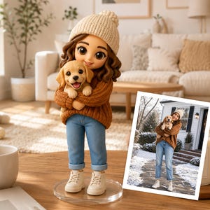 Può includere: Una statuetta personalizzata di una persona con capelli castani ondulati, un berretto in maglia color crema e un maglione marrone, che tiene in braccio un cucciolo dorato. La figura indossa jeans azzurri e stivali bianchi su base circolare.