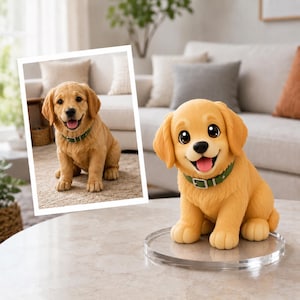 May include: A golden retriever puppy figurine with large dark eyes and a wide smile, wearing a green collar with a silver buckle. The puppy is sitting on a clear circular acrylic base, and a framed photograph of the same puppy is displayed nearby.