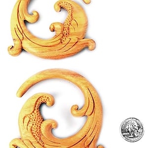 May include: Two wooden ear gauges with a carved floral design. The gauges are about the size of a US quarter.