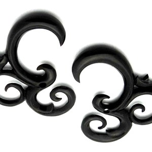 May include: A pair of black, ornate, wooden ear gauges. The gauges are shaped like a stylized swirl with a small flower detail.