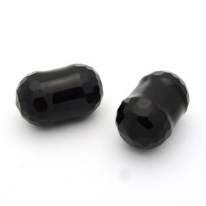 May include: Two black faceted glass beads, each with a slightly rounded shape.