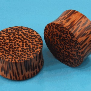 May include: Two wooden ear gauges with a brown and black leopard print pattern. The gauges are made of wood and have a smooth finish.