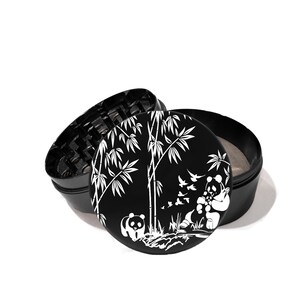 May include: Black metal grinder with a white design of bamboo trees and pandas. The grinder has a screen and a compartment for storing herbs.
