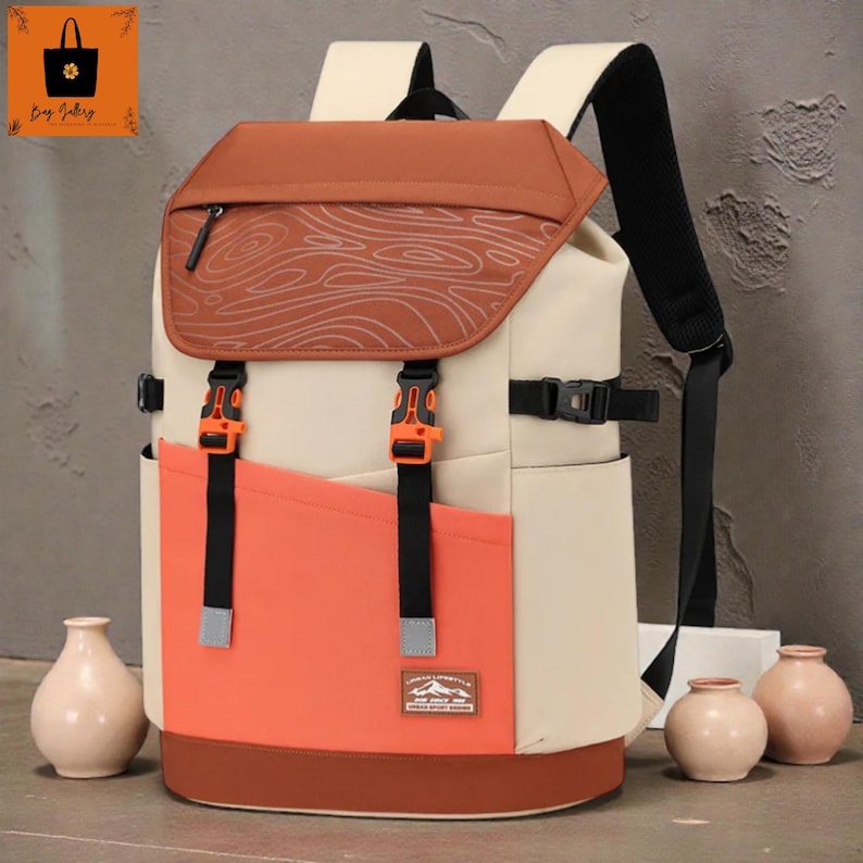 May include: A multi-tone backpack with a brown top flap featuring a wood grain design, orange accents, and cream-coloured body. The backpack has adjustable straps, black buckles, and a front pocket. The bag has a small patch that reads "URBAN ADVENTURE SPORT DESIGN."
