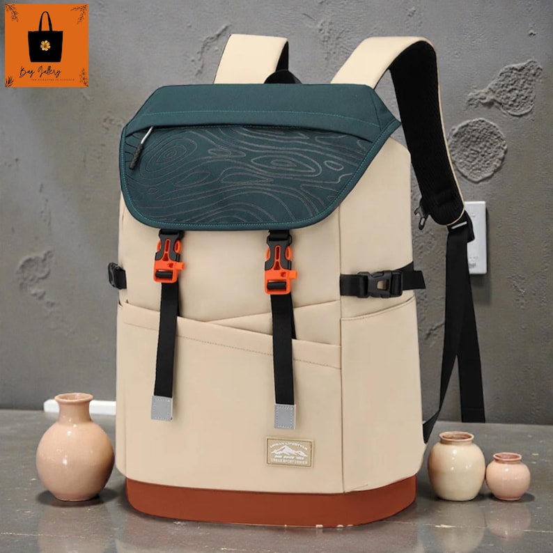 May include: A beige and green backpack with black straps and orange buckles. The top flap is green with a wood grain design. The bottom of the backpack is brown. The backpack has a small pocket on the front.