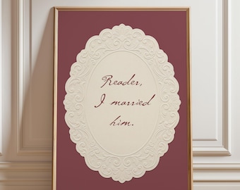 May include: A rectangular framed wall art piece featuring a deep maroon background. In the center, an oval cream-colored plaque with an ornate, embossed scrollwork border displays the dark maroon text: Reader, I married him. The frame is thin and light wood.