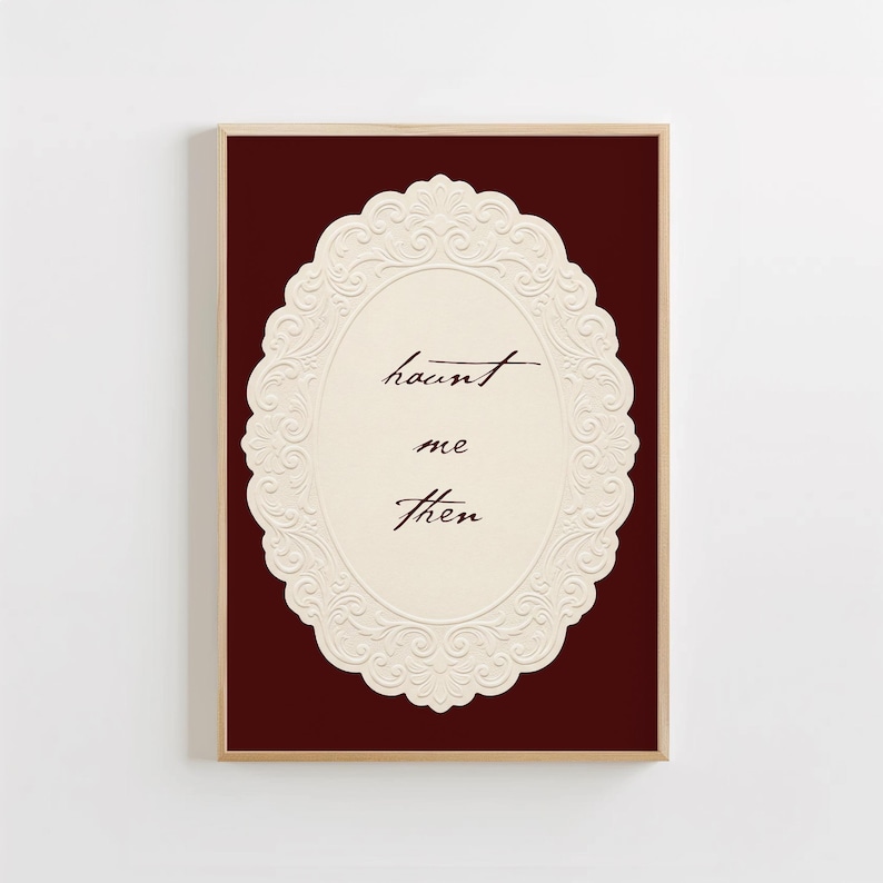May include: A rectangular wall art print featuring a deep burgundy background and a central cream-colored oval frame with an embossed floral border. The text "haunt me then" is written in the center in a dark brown cursive script font.