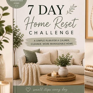 May include: A book cover with the title "7 DAY Home Reset Challenge" in a stylish font. The cover features a living room scene with a sofa, pillows, and decorative items. The text on the cover reads "A simple plan for a calmer, cleaner, more manageable home."