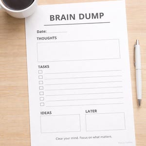 May include: A white "Brain Dump" notepad with sections for thoughts, tasks, ideas, and later, alongside a white pen and a cup of coffee. The notepad has the text "Clear your mind. Focus on what matters."