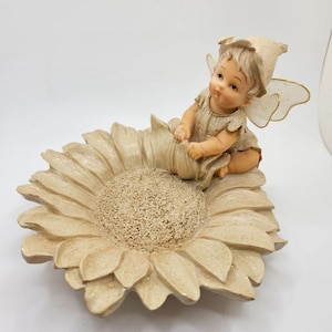 May include: A set of three ceramic mugs with a speckled, cream-colored glaze. Each mug features a different hand-painted floral design in shades of blue, green, and yellow. The mugs have a simple, rounded shape and a comfortable handle.