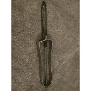 Può includere: Una paletta per gelato vintage con un manico scuro e una paletta in metallo color argento. La paletta ha un manico lungo e sottile e una testa a paletta curva e rettangolare. Lo strumento è progettato per raccogliere il gelato.