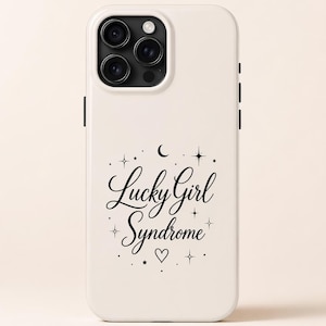Puede incluir: Funda de teléfono blanca con un módulo de cámara negro y la frase "Lucky Girl Syndrome" en letra cursiva, rodeada de estrellas, una luna creciente y un corazón.