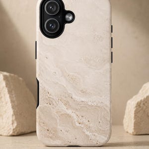 Może przedstawiać: Beżowe etui na telefon z marmurowym wzorem. Etui posiada czarny moduł aparatu i czarne akcenty po bokach. Wykonane z wytrzymałego materiału, chroni telefon przed zarysowaniami i upadkami.