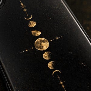Può includere: Custodia per telefono nera con un design dorato delle fasi lunari. Il design include lune crescenti, mezze lune e una luna piena, insieme a stelle e linee tratteggiate. La custodia ha una finitura lucida.