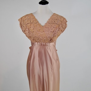 May include: A blush pink satin dress with a lace bodice. The lace is a delicate floral pattern in a slightly darker shade of pink.