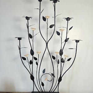 Peut inclure: Un candélabre en métal noir doté de sept bougeoirs disposés sur des tiges fines et incurvées. La structure est ornée de nombreuses feuilles en métal noir et de plusieurs petites fleurs de rose en céramique de couleur crème.