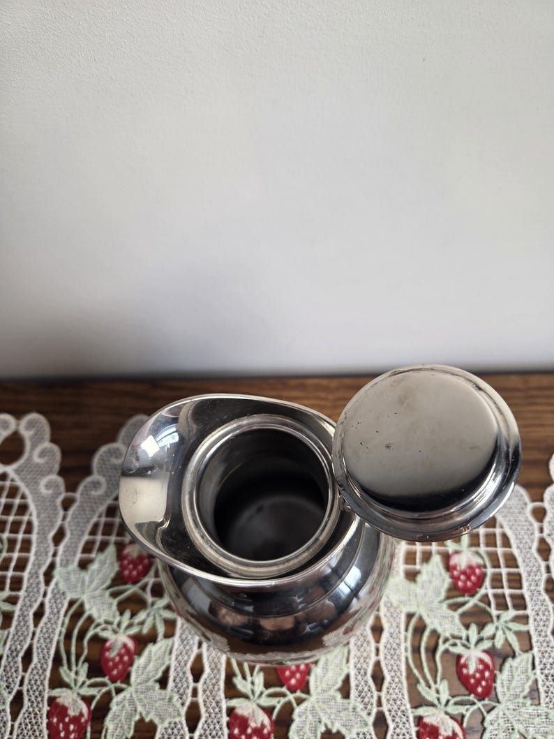 Puede incluir: Una taza de cer&aacute;mica blanca con un asa negra y el texto "But First, Coffee" en negro, con una fuente de estilo manuscrito. La taza est&aacute; sobre una superficie blanca.
