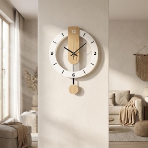 Peut inclure: Une horloge murale moderne avec un cadran circulaire blanc et des aiguilles noires. L'horloge est dotée d'un pendule en bois et d'un élément décoratif en bois en haut. Les chiffres 3, 6, 9 et 12 sont marqués de traits noirs.