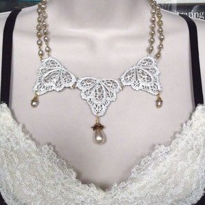 May include: A white lace necklace with a three-piece design and a pearl drop pendant. The necklace is made of delicate lace and features a gold chain.