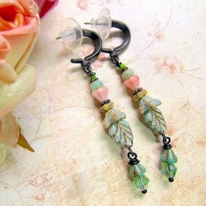 May include: A pair of dangle earrings with a black metal hook and a chain of turquoise, pink, and green beads. The beads are shaped like leaves and flowers.