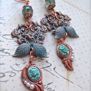 May include: A pair of long, dangling earrings with a copper filigree design. The earrings feature turquoise and green glass beads, and white pearl accents.