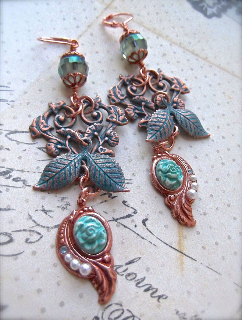 May include: A pair of long, dangling earrings with a copper filigree design. The earrings feature turquoise and green glass beads, and white pearl accents.