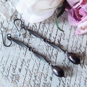 May include: A pair of dangle earrings with black teardrop-shaped beads and silver-toned metal accents.