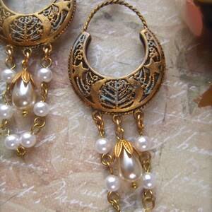 Puede incluir: Pendientes de tono dorado con un dise&ntilde;o de media luna y cuentas de perlas colgantes. Los pendientes tienen un estilo vintage y son perfectos para agregar un toque de elegancia a cualquier atuendo.