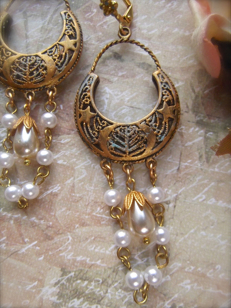 Puede incluir: Pendientes de tono dorado con un dise&ntilde;o de media luna y cuentas de perlas colgantes. Los pendientes tienen un estilo vintage y son perfectos para agregar un toque de elegancia a cualquier atuendo.