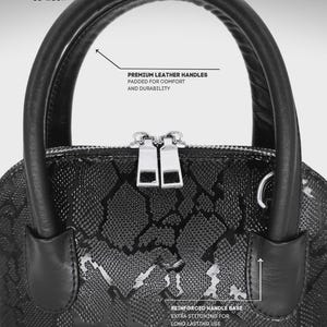 May include: A black handbag with a snakeskin pattern, featuring premium leather handles and reinforced handle base with extra stitching. The bag has a silver zipper and the text "LE MESH".