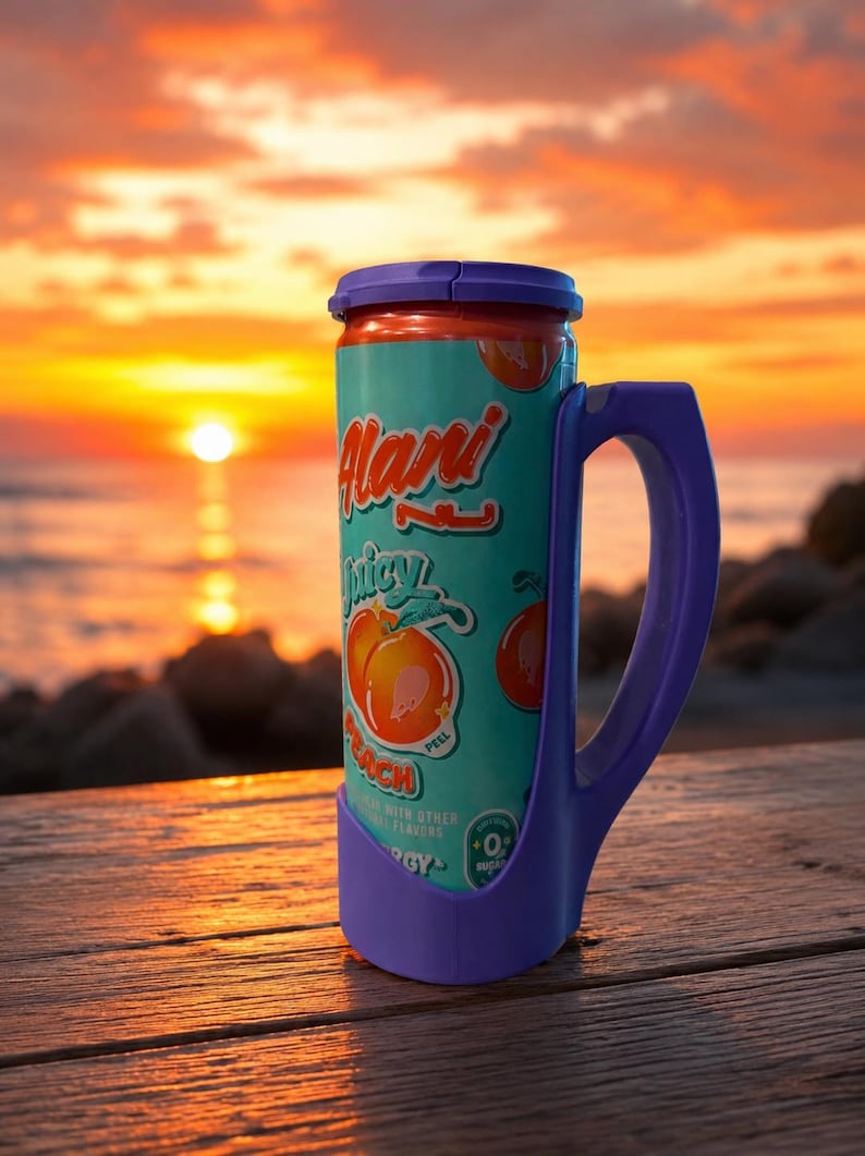 Może przedstawiać: Turkusowa i pomarańczowa puszka napoju Alani Nu Juicy Peach z fioletowym uchwytem i podstawą. Puszka zawiera ilustracje i tekst brzoskwini. Tło przedstawia zach&oacute;d słońca nad oceanem.