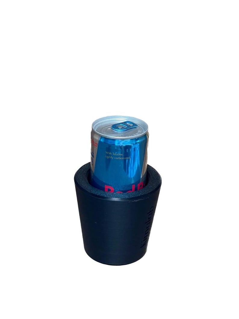 May include: A blue and silver Red Bull energy drink can inside a navy blue insulated beverage holder. The can has blue and silver text. The beverage holder has the text "kiinoolab" on the side.