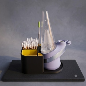 May include: A lavender electronic vaporizer with a clear glass conical attachment sits beside a black and yellow organizer. The organizer holds a collection of white cotton swabs and a single metal tool with a bright green silicone tip.