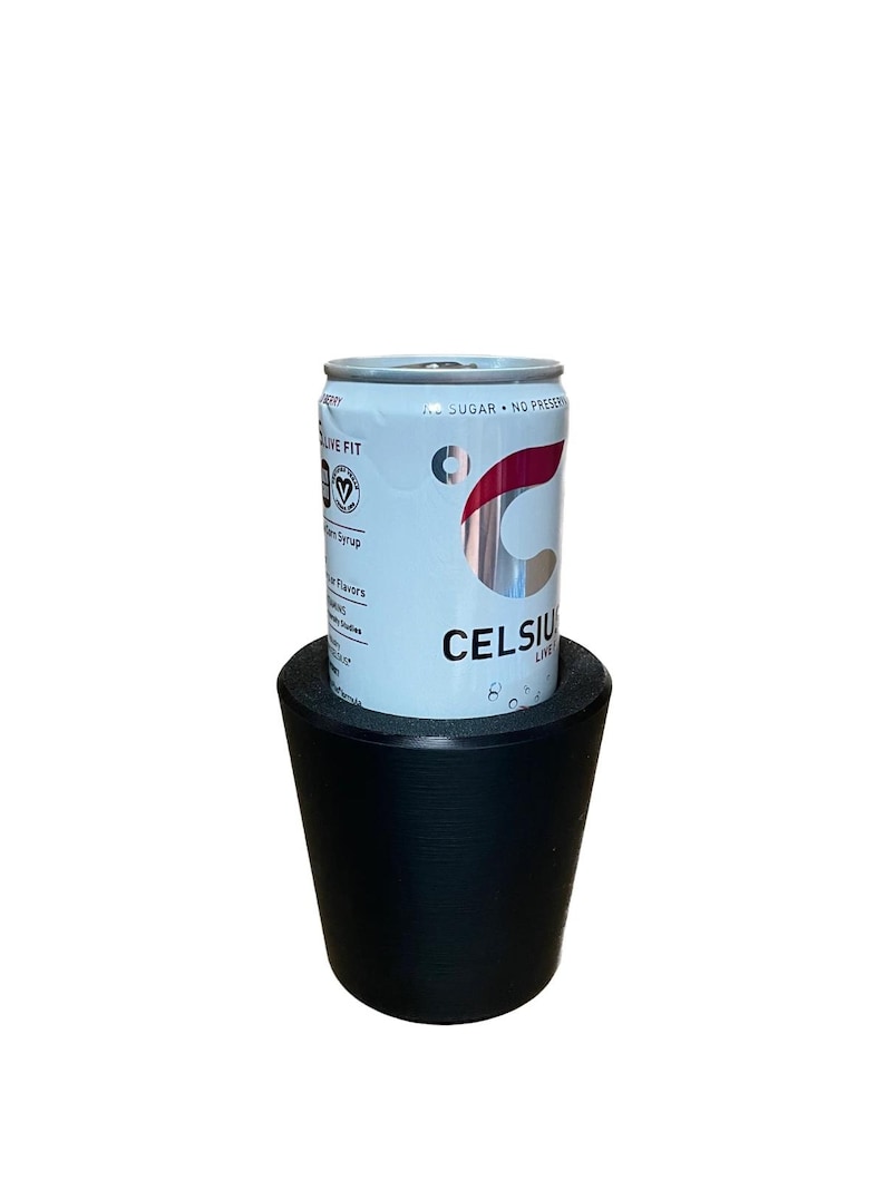 May include: A light blue Celsius energy drink can with red and silver accents, resting on a black, conical drink holder. The can features the text "CELSIUS LIVE" and "SUGAR - NO PRESERVATIVES".