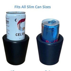 May include: Two black can coolers, each holding a slim can. One cooler holds a Celsius can, the other a Red Bull can. The text "Fits All Slim Can Sizes" is above the coolers. These are designed to keep beverages cold.