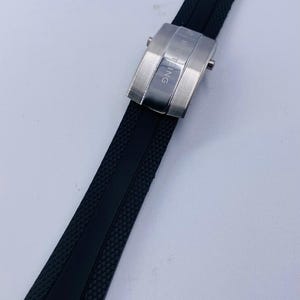 K&ouml;nnte beinhalten: Ein schwarzes Kautschuk-Uhrenarmband mit strukturierter Oberfl&auml;che und einer Faltschlie&szlig;e aus geb&uuml;rstetem Edelstahl. Die Schlie&szlig;e ist mit dem eingravierten Schriftzug BREITLING und einem kleinen Logo versehen, das einen sicheren Verschluss bietet.
