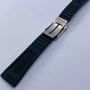 K&ouml;nnte beinhalten: Ein schwarzes Kautschuk-Uhrenarmband mit einer silberfarbenen Metall-Faltschlie&szlig;e. Das Armband hat eine gerippte Textur und das Wort BREITLING ist eingepr&auml;gt. Der Text 22-18 ist am Ende des Armbands deutlich zu erkennen.