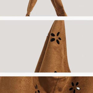May include: Close-up shots of a brown suede tote bag. The bag features a handle and a body with flower-shaped cutouts. The stitching is visible, and the bag appears to be made of a soft material. The bag is a neutral color.