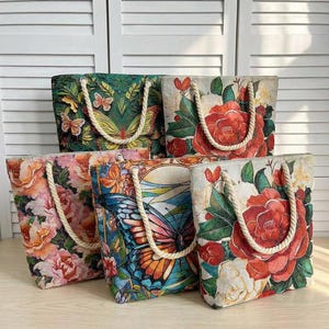 Puede incluir: Cinco bolsos tote con diseños florales y de mariposas. Los bolsos tienen asas de cuerda y están decorados con colores vibrantes. Los bolsos tienen forma rectangular y están hechos de tela tejida.