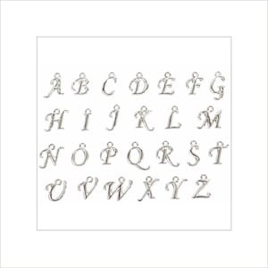Pode incluir: Berloques de alfabeto prateados, cada um com uma argola para prender a uma pulseira ou colar. As letras de A a Z são exibidas em fonte cursiva. Os berloques estão dispostos em fileiras sobre um fundo branco.