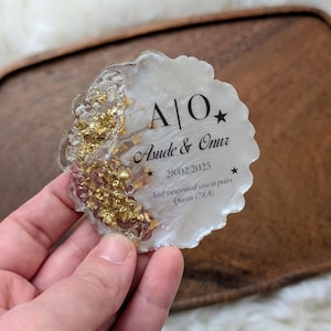 May include: A decorative coaster with a white and gold design. The coaster features the names "Asude & Onur" and the date "28/02/2025". The text "And we created you in pairs Quran (78:8)" is also included.