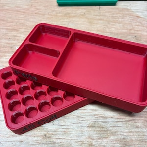 Pode incluir: Uma bandeja de armazenamento de pl&aacute;stico vermelho com v&aacute;rios compartimentos e uma bandeja vermelha separada com uma grade de orif&iacute;cios circulares. A lateral da bandeja tem o texto preto em relevo .45 Colt e a palavra Parts.