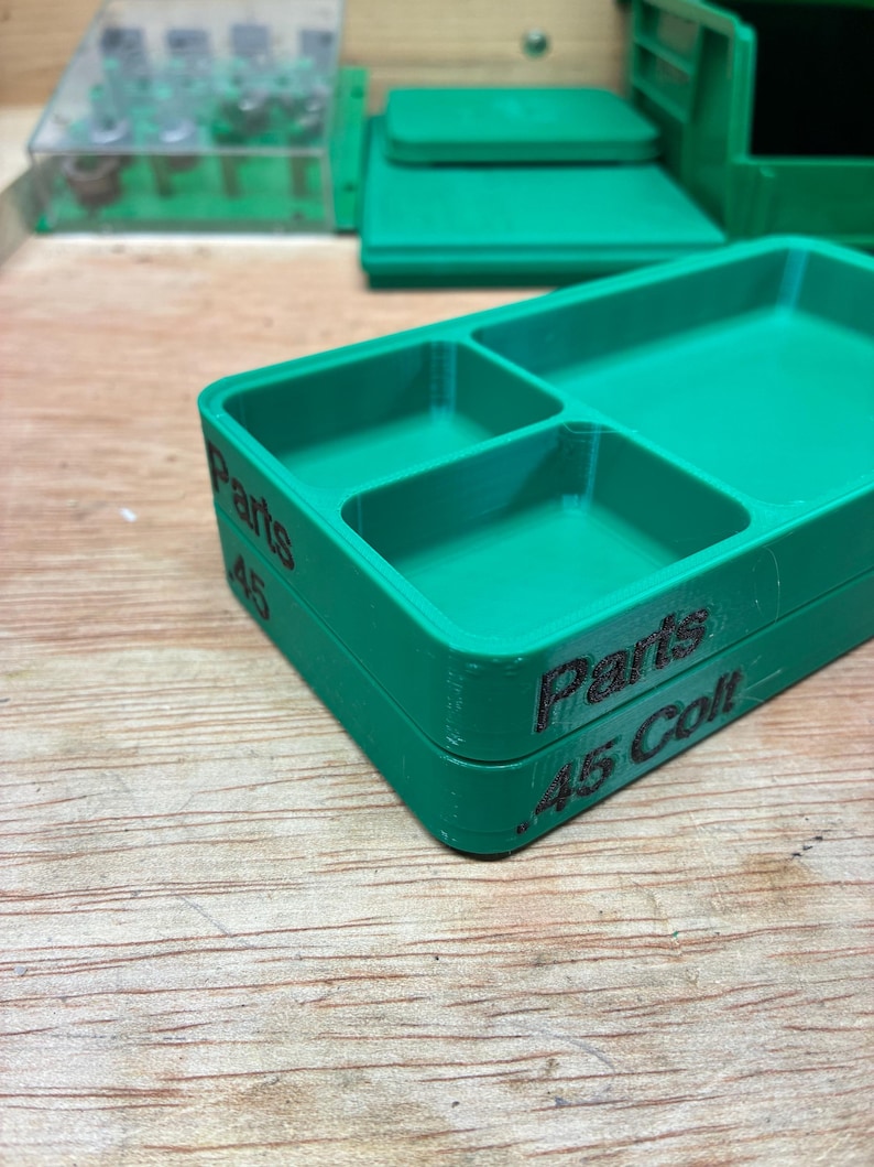Pode incluir: Uma bandeja de armazenamento de pl&aacute;stico verde com tr&ecirc;s compartimentos distintos. A lateral da bandeja apresenta um texto impresso em preto que diz Parts e .45 Colt. A bandeja tem formato retangular com cantos arredondados e acabamento liso.