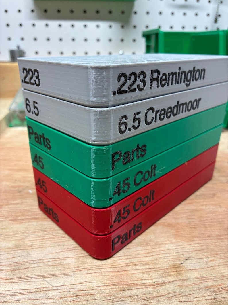 Pode incluir: Uma pilha de seis bandejas retangulares de pl&aacute;stico nas cores branca, verde e vermelha. As laterais possuem texto em preto, incluindo .223 Remington, 6.5 Creedmoor, .45 Colt e Parts. Cada bandeja apresenta um padr&atilde;o de grade no topo.