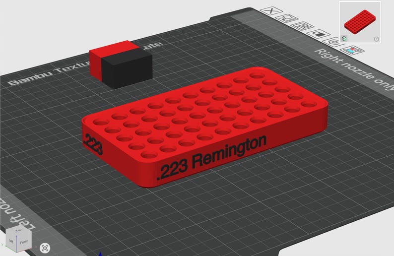 Pode incluir: Uma bandeja retangular de pl&aacute;stico vermelho para armazenamento de muni&ccedil;&atilde;o, com uma grade de orif&iacute;cios circulares para cartuchos. A lateral da bandeja tem impresso em preto o texto .223 Remington. Um pequeno bloco vermelho e preto est&aacute; posicionado ao lado.