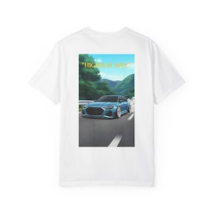 Könnte beinhalten: Weißes T-Shirt mit einer Grafik eines blauen Autos auf einer Straße, vor grünem Gebirge. Der Text "HIGHWAY SPEC" befindet sich über dem Auto. Das Design ist mittig auf dem T-Shirt platziert.