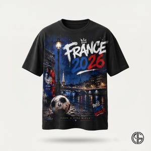 May include: A black short-sleeve t-shirt featuring a graphic print of a Parisian night scene with a soccer ball, the Eiffel Tower, a street lamp, and the text "FRANCE 2026", "PARIS SAINT WINNER", and "FIERS D'ETRE BLEUS" with a rooster emblem.
