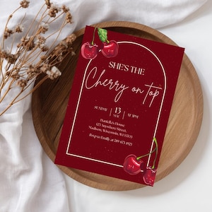 Pode incluir: Um cartão de convite retangular com fundo vermelho escuro e ilustrações de cerejas em aquarela no topo e na base. O texto diz: SHE'S THE Cherry on top, SUNDAY 13 MAY AT 3PM, Daniella's House, 123 Anywhere Street, Madison, WI 53703.